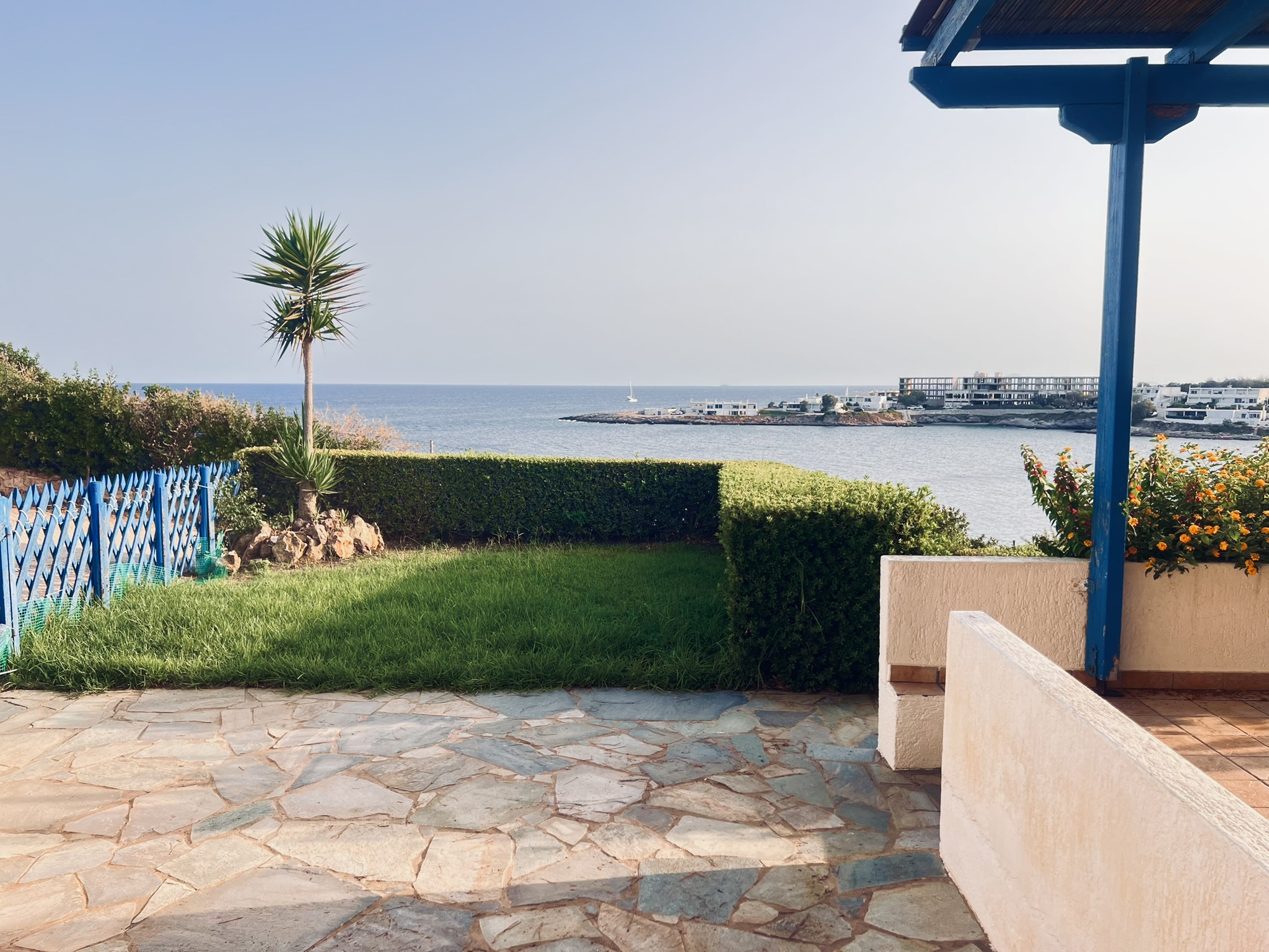 Private garden with stone paving, lawn, yucca tree, and sea view