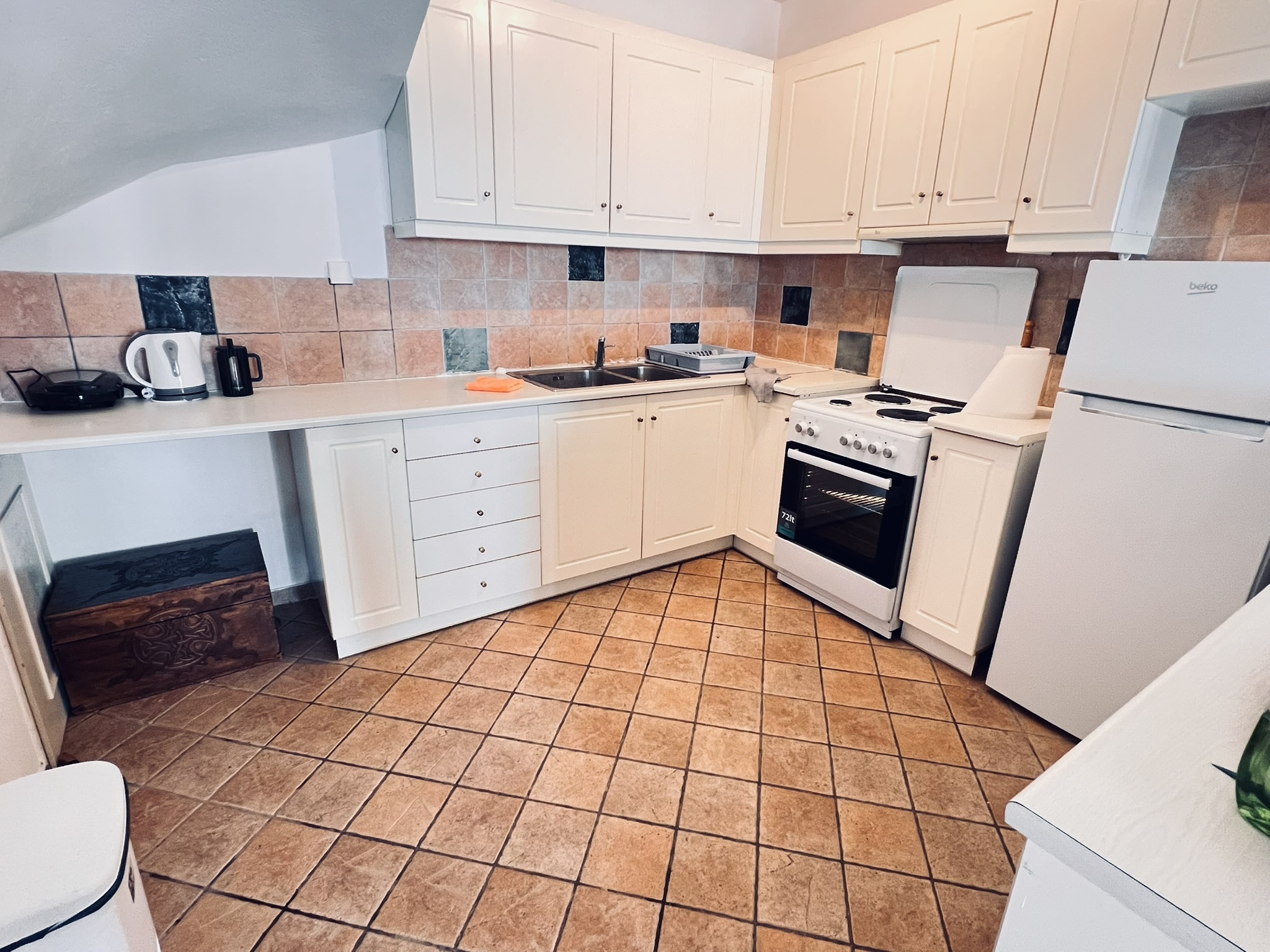The fully equipped kitchen — white cabinets, full-size refrigerator, oven and cooktop, and breakfast bar