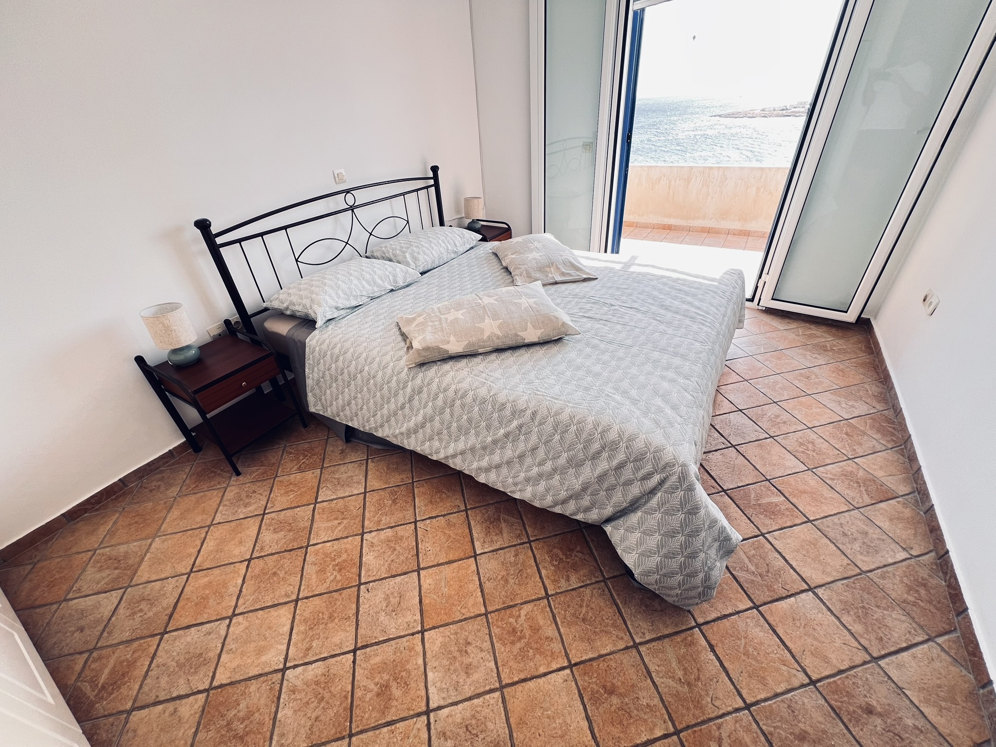 Master bedroom detail — wrought-iron bed, reading lamps, and terracotta floor tiles