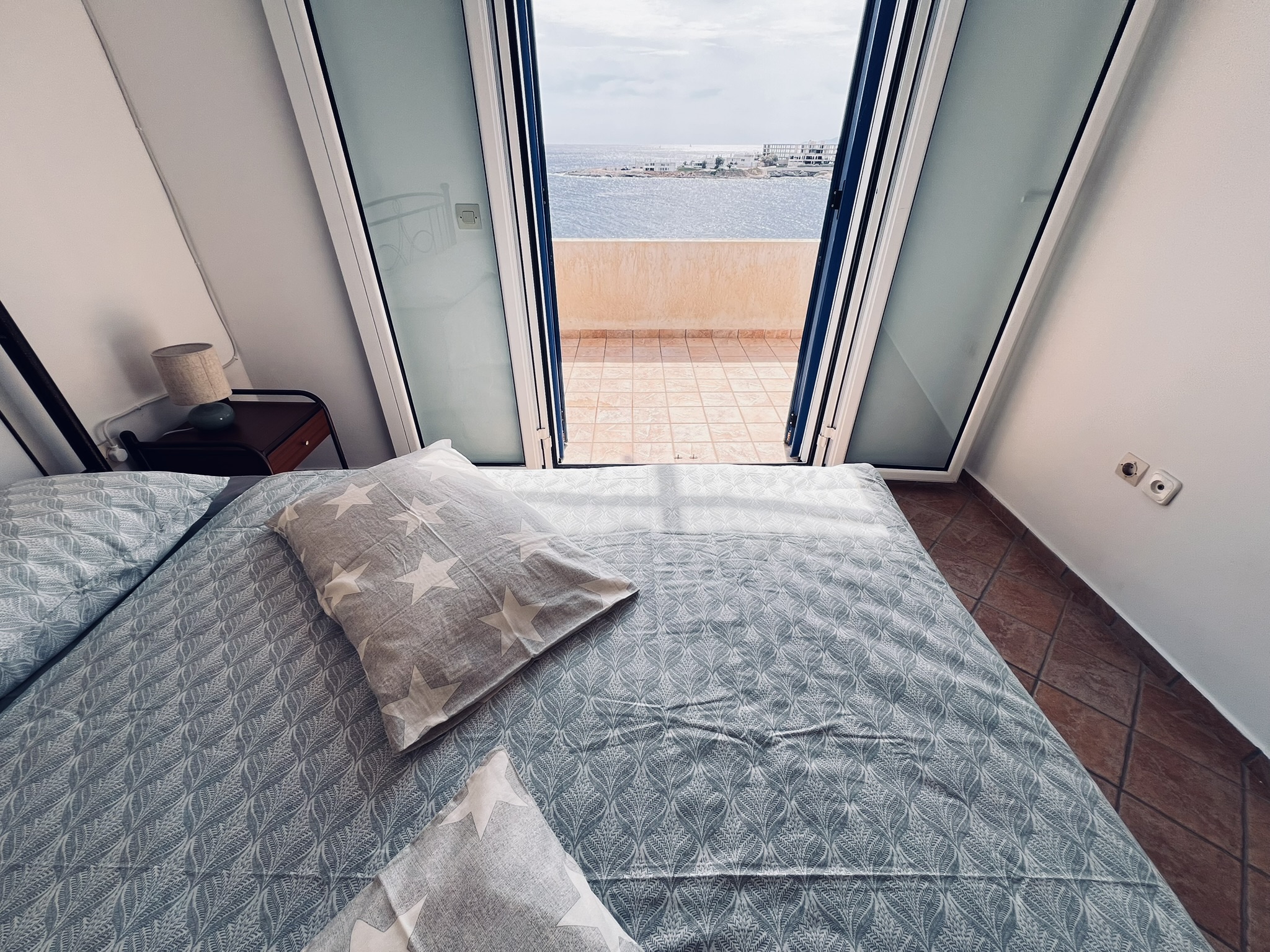 The master bedroom on the first floor with open door to the sea-facing balcony and the Aegean beyond